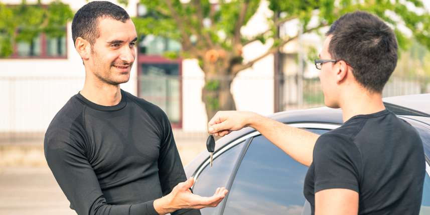 Happy satisfied young man receiving car keys after second hand s