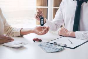 Car rent agent manager holding key of new car giving to woman cl